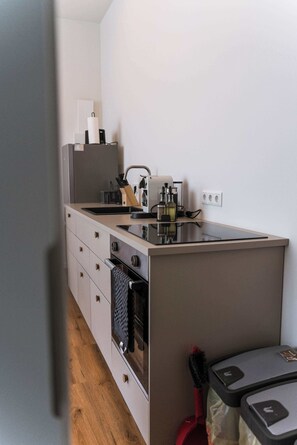 A compact kitchenette with a built-in oven, a sink, and a coffee maker. - Design apartment by the park with parking (Celle)