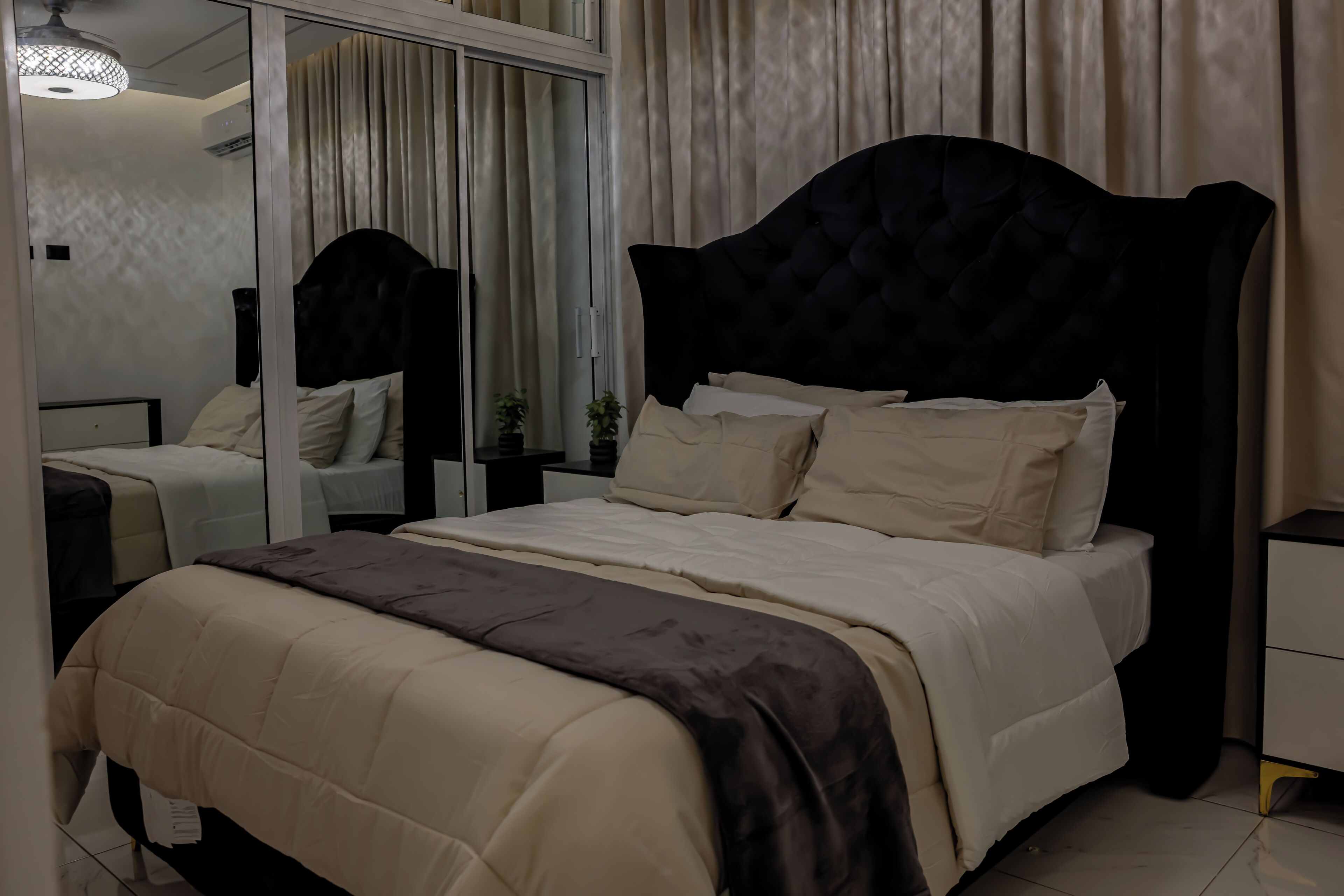 Ein Schlafzimmer mit einem großen Bett, einem Nachttisch, einem Spiegel und einer Deckenleuchte.