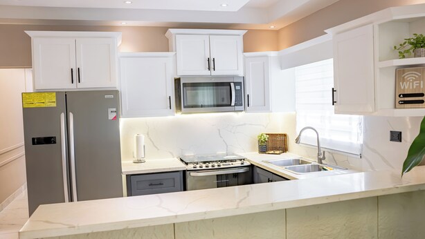A modern kitchen with white cabinetry, a built-in microwave, a gas stove, and a sink. - Modern Luxury Apartment in Baní (Baní)