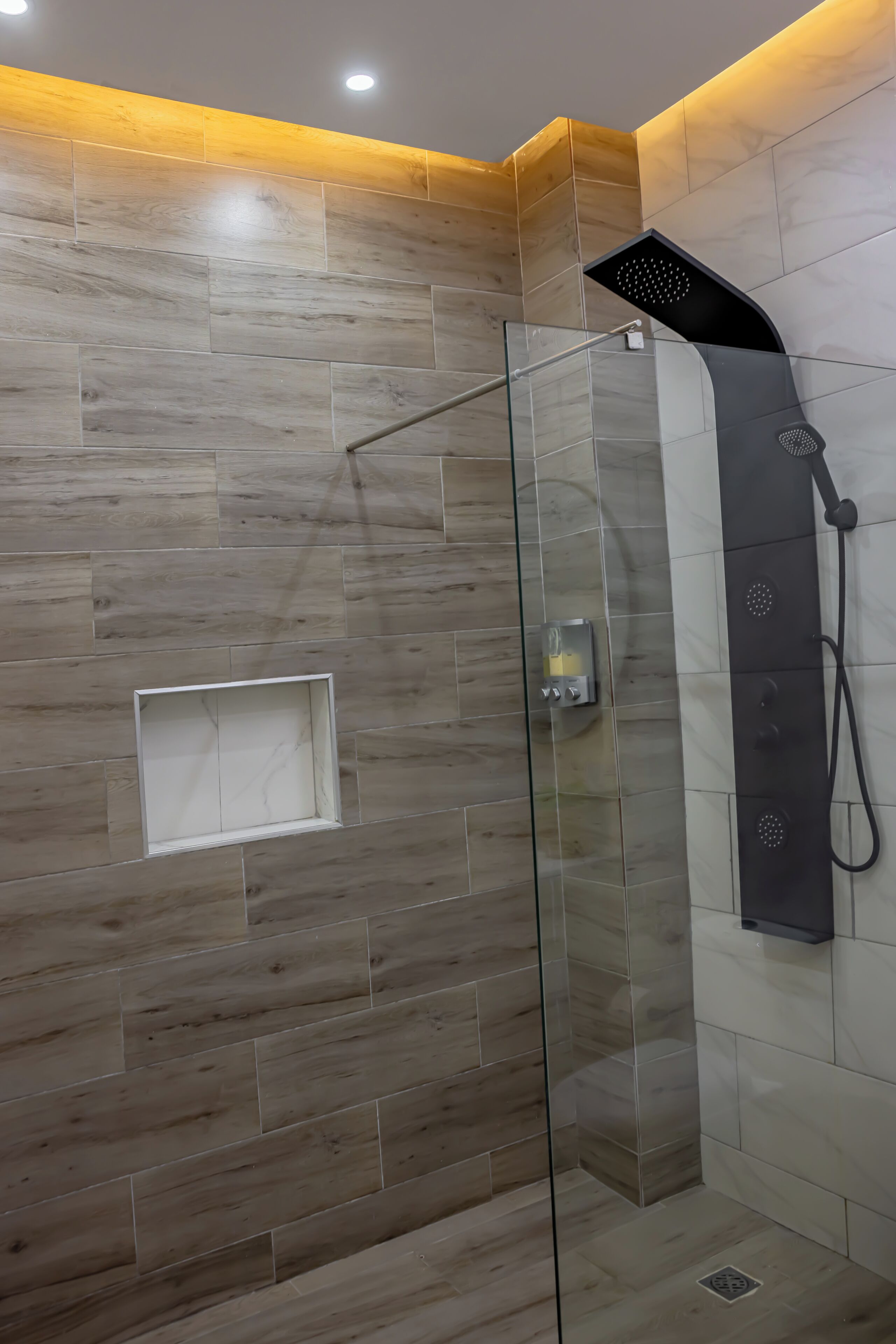 Eine begehbare, gläserne Dusche mit modernem Design, Bedienfeld und einer kleinen Ablagefläche.