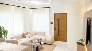 A modern living room with a sectional sofa, a coffee table, and a TV. - Modern Luxury Apartment in Baní (Baní)