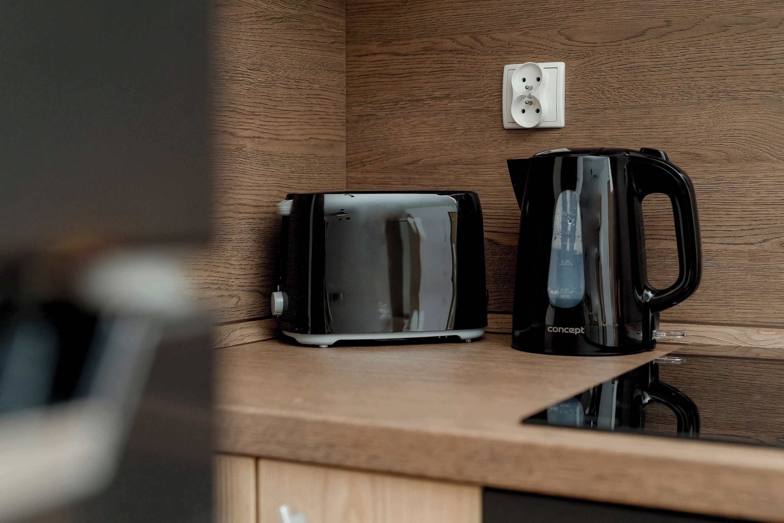 A kitchenette with a toaster and a coffee maker on a wooden countertop.