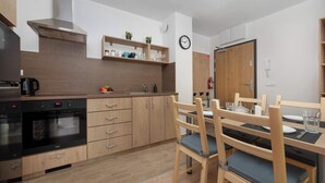 Ett modernt kök med träskåp, en inbyggd ugn och en matplats med ett träbord och stolar.