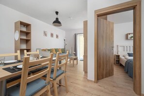 A modern, well-lit room with a wooden dining table, chairs, and a sofa. - Cosy Apartment with Terrace | Parking | Sowie Skały (Szklarska Poręba)