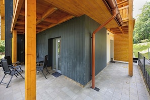 A covered outdoor area with a patio, a table with chairs, and a door leading to an interior space. - Cosy Apartment with Terrace | Parking | Sowie Skały (Szklarska Poręba)