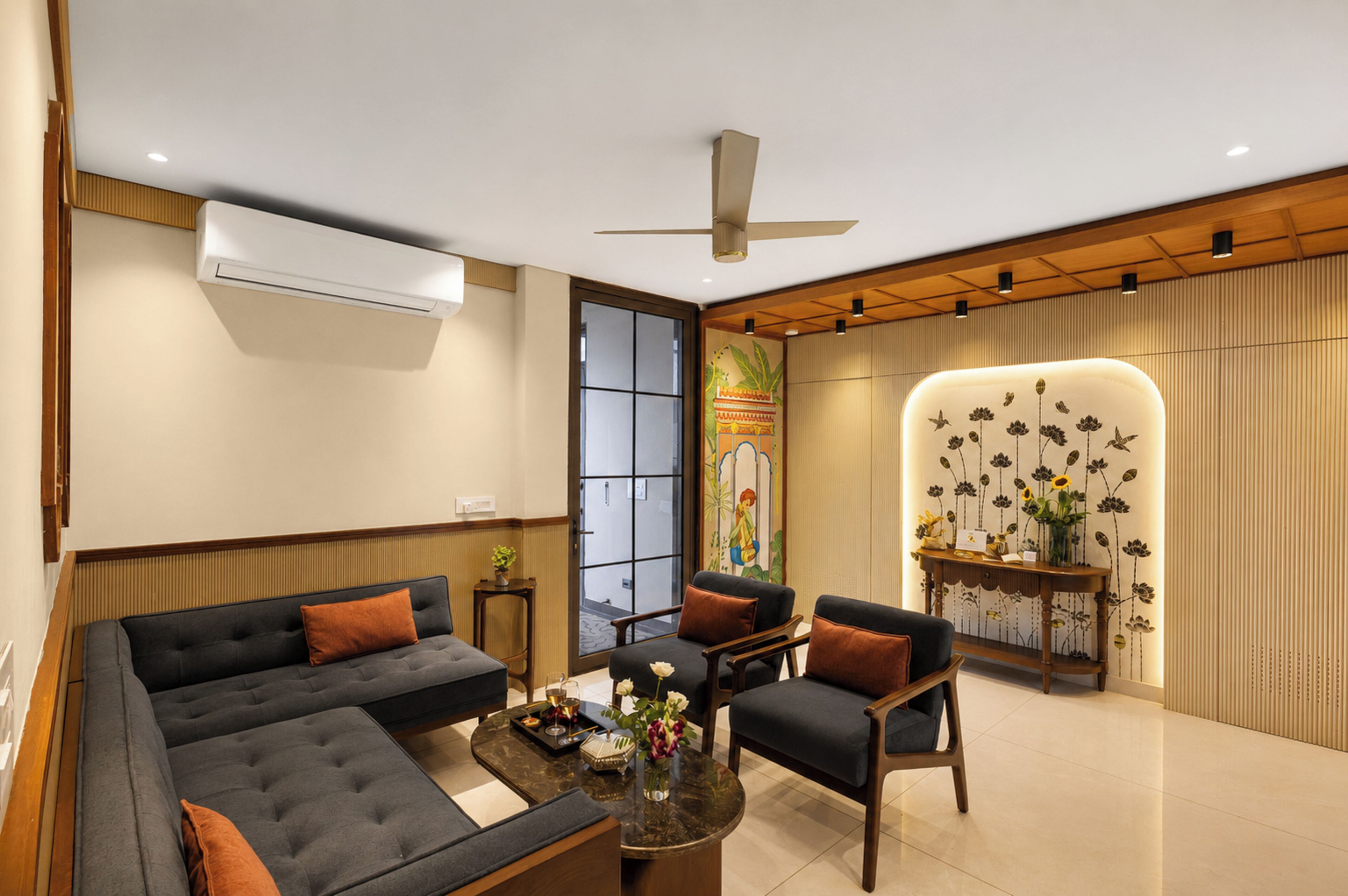 Una sala de estar moderna con un sofá, sillones, una mesita de centro y una pared decorativa con motivos florales.