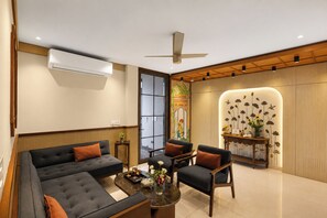 Uma sala de estar moderna com sofá, poltronas, mesa de centro e parede decorativa com padrões florais.