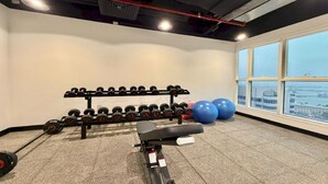Un gimnasio con una prensa de banca, un soporte para mancuernas y pelotas de ejercicio azules.