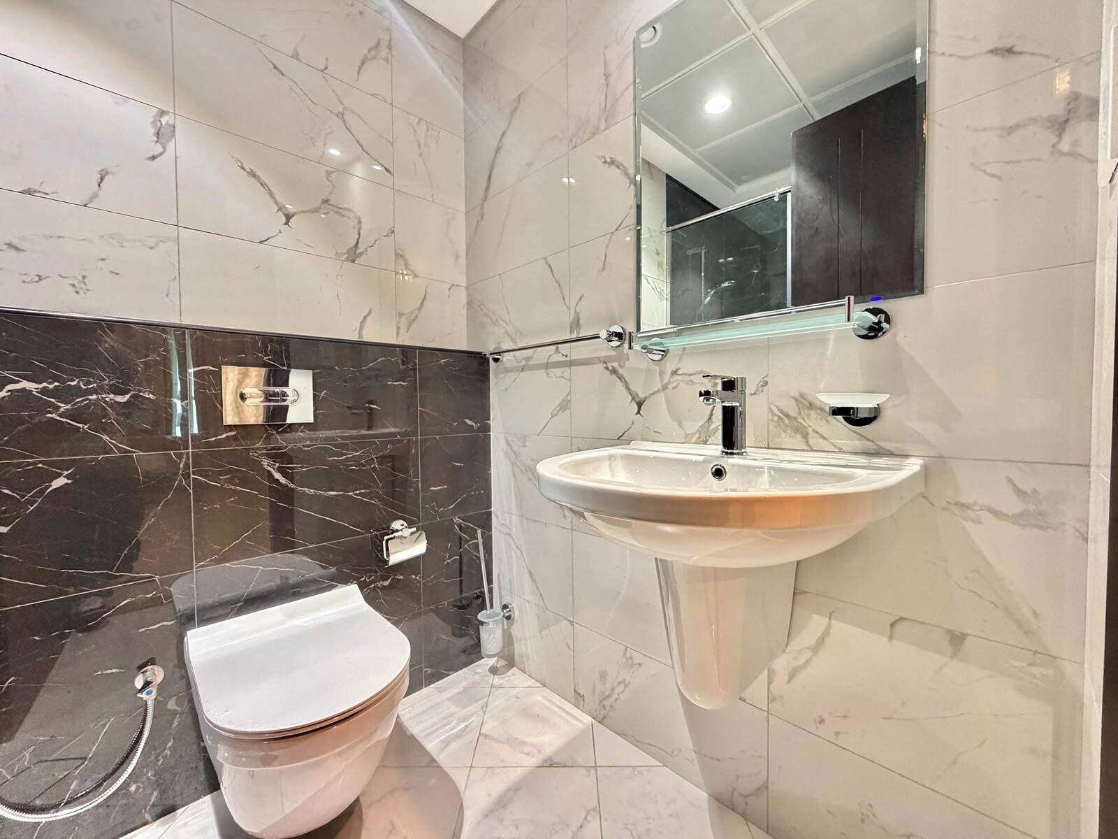 Un baño con inodoro, lavamanos y espejo.