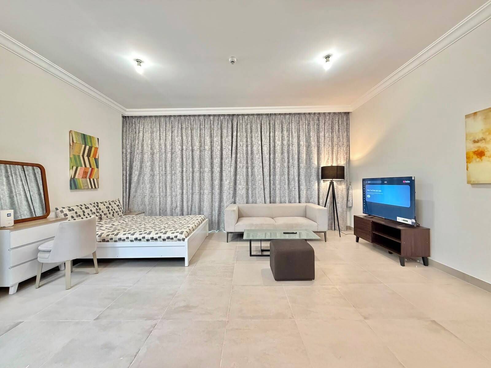 A modern living room with a bed, sofa, TV, and a lamp.