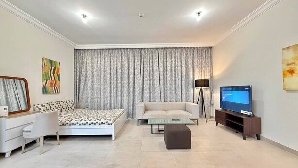 Una sala moderna con cama, sofá, televisor y lámpara.