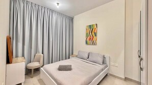 Un dormitorio con cama, una silla, un armario y un cuadro en la pared.