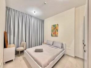 Un dormitorio con cama, una silla, un armario y un cuadro en la pared.