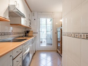 Eine Küche mit weißen Schränken, einer Holzarbeitsplatte und einer gefliesten Spritzschutzwand.