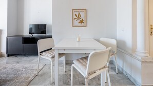 A modern dining area with a white table and chairs, a framed artwork on the wall, and a television in the background. - Se or o de Aloha in Marbella (Marbella)