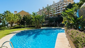 A swimming pool with a clear blue water surface, surrounded by a well-maintained garden with various plants and a stone wall. - Se or o de Aloha in Marbella (Marbella)