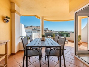 A balcony with a wooden table and chairs, a potted plant, and a view of buildings in the distance. - Se or o de Aloha in Marbella (Marbella)