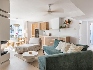 A modern living space with a sofa, a dining area, and a kitchenette. - Los Naranjos Modern 2 Bedroom Penthouse With Views (Marbella)
