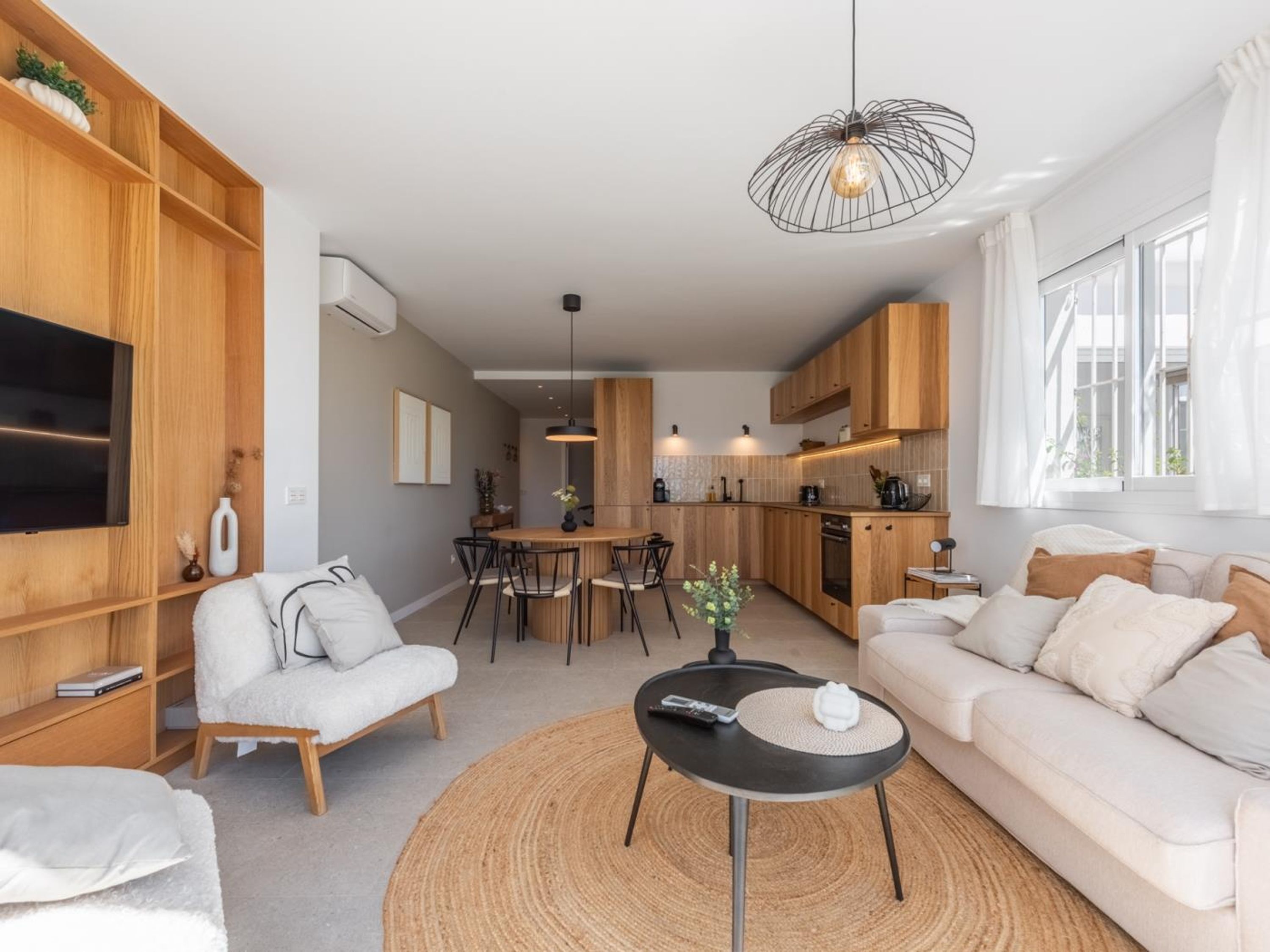 A modern living room with a sofa, a coffee table, and a TV mounted on the wall.