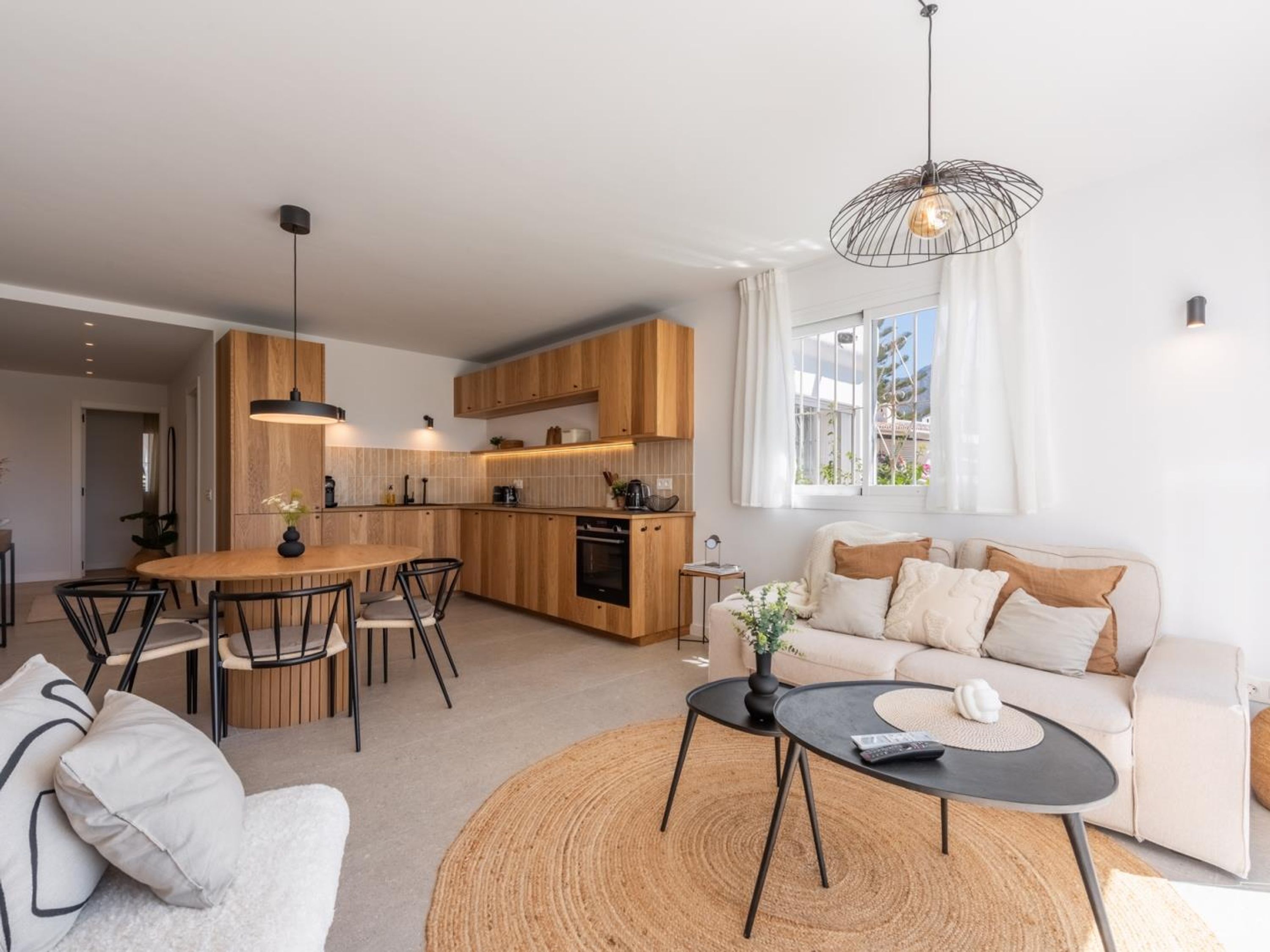 A modern living space with a dining area, kitchen, and seating area.