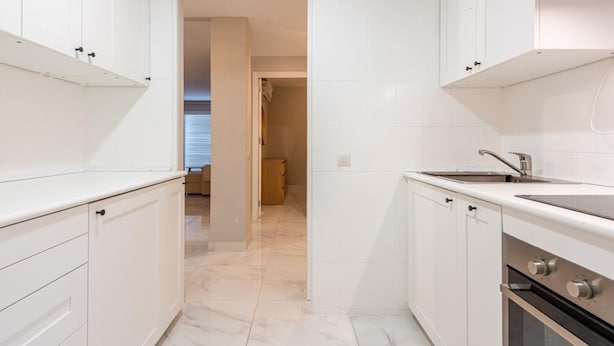 A modern kitchen with white cabinetry, a built-in oven, and a countertop with a sink. - Azahara1 Mountain Views and Frontline Golf (Marbella)