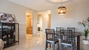 A dining area with a table and chairs, a hanging light fixture, and a potted plant. - Azahara1 Mountain Views and Frontline Golf (Marbella)