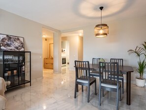 A dining area with a table and chairs, a hanging light fixture, and a potted plant. - Azahara1 Mountain Views and Frontline Golf (Marbella)