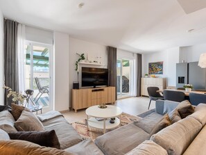 A modern living room with a sofa, a coffee table, a TV, and a dining area with chairs. - Locrimar Family Apartment With Amazing Location (Marbella)