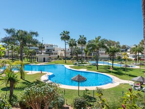 A swimming pool surrounded by palm trees and a clear blue sky. - Locrimar Family Apartment With Amazing Location (Marbella)