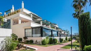 A modern two-story house with a covered patio, a paved driveway, and well-maintained landscaping.