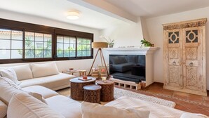 A spacious living room with a large sectional sofa, a television, and a decorative cabinet. - Villa Amapolas 222 in Marbella (Marbella)