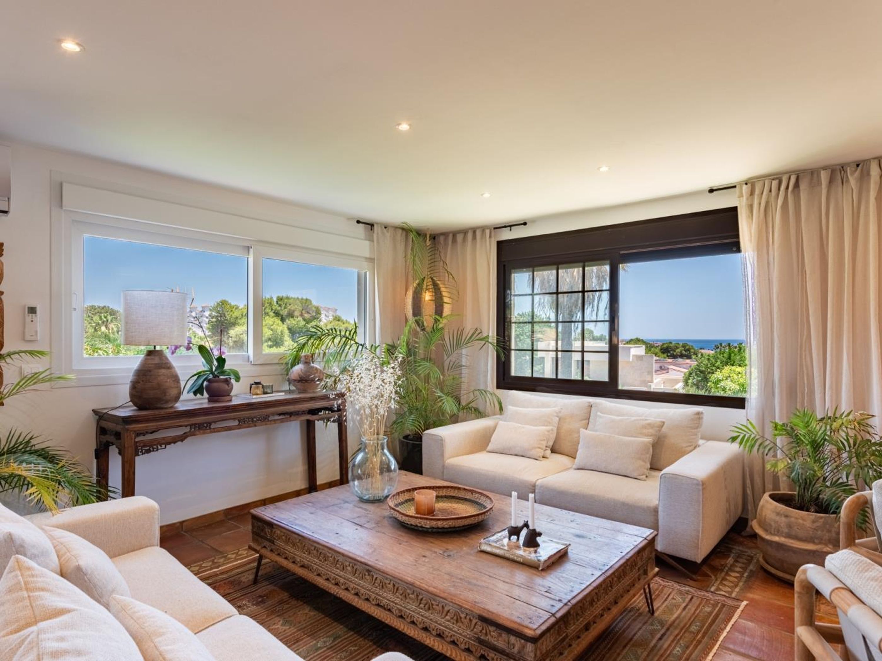A spacious living room with a large window, a wooden coffee table, and a beige sofa.