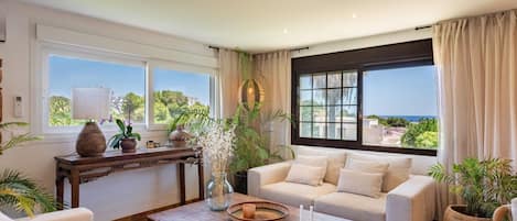 A spacious living room with a large window, a wooden coffee table, and a beige sofa.