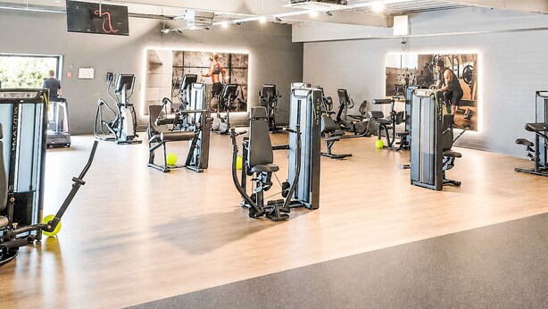 A gym with various exercise machines, a wooden floor, and a high ceiling with exposed beams. - Küstenblick by Interhome (Burhave)