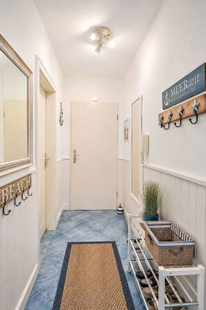 A hallway with a blue-tiled floor, a white door, and a wall-mounted sign reading 'MEERZEIT ist die schönste Zeit.' - Meeresrauschen by Interhome (Burhave)