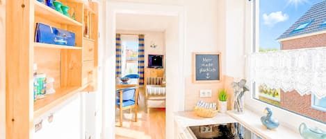 A kitchen with wooden cabinets, a stove, and a window with a view of a house.