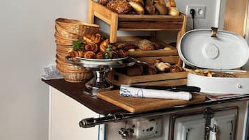 Una encimera de cocina con varios productos horneados, una cesta de pan, una bandeja y una olla sobre la estufa.