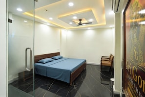 A modern bedroom with a bed, a chair, and a glass partition. - Sri Gopal Guest House  (Varanasi)
