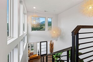 Ein modernes Interieur mit Treppe, großen Fenstern und hängenden Lampen.