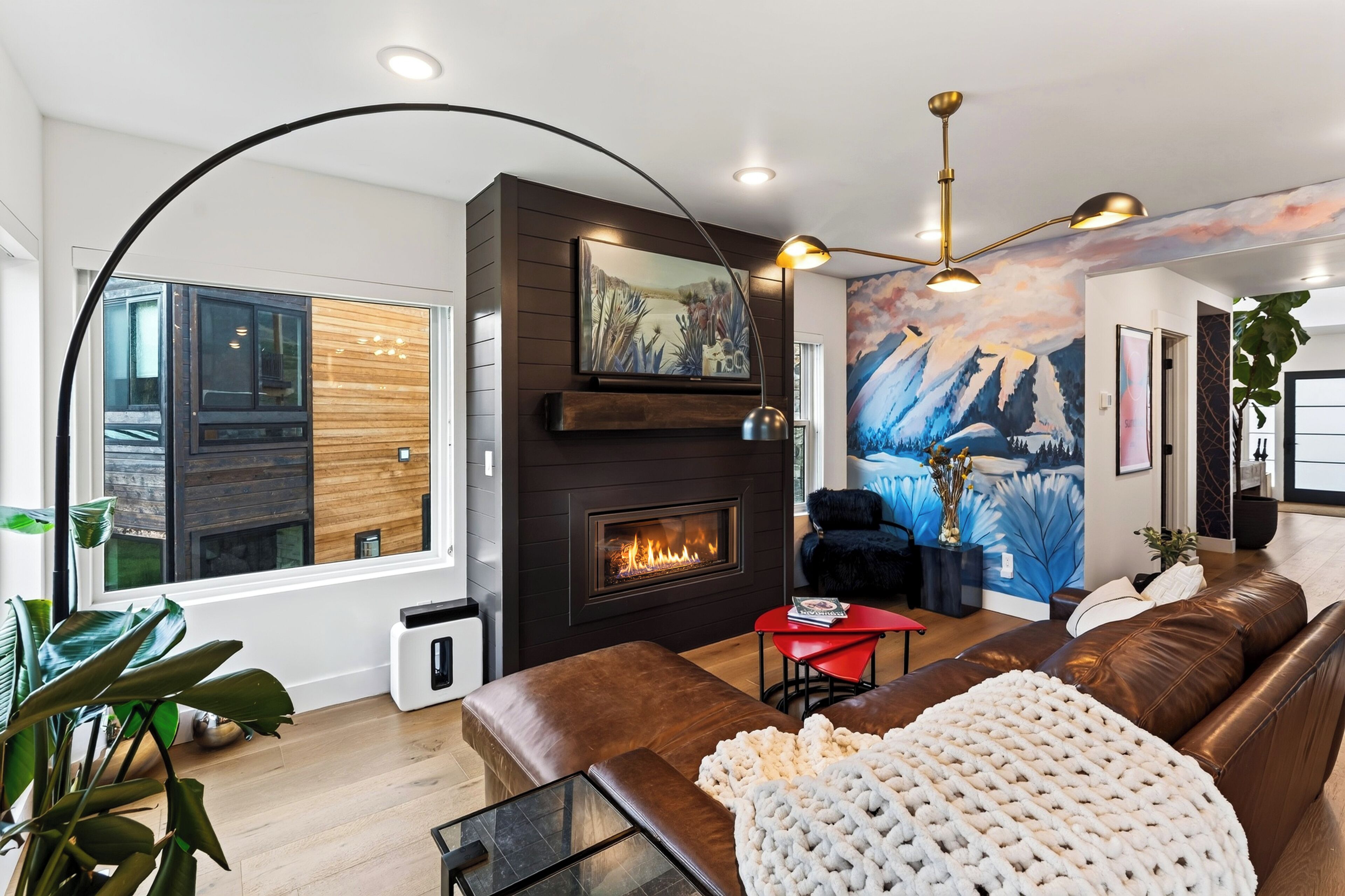A modern living room with a fireplace, leather sofa, and a large window.