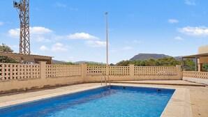 A rectangular swimming pool with clear blue water, surrounded by a beige wall with circular cutouts. - Casa Dolo · Beachfront Apartment with Pool, Elevator, and WiFi (Tavernes de la Valldigna)