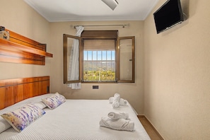 Habitación de hotel con cama, ventana con vistas, televisión de pantalla plana y cabecero de madera.
