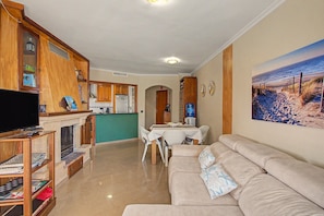 A living room with a television, sofa, and a painting of a beach scene.