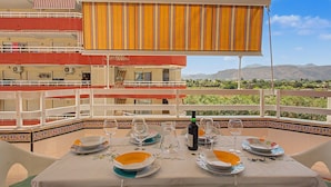 A dining area with a table set for four, overlooking a mountainous landscape. - Casa Dolo · Beachfront Apartment with Pool, Elevator, and WiFi (Tavernes de la Valldigna)