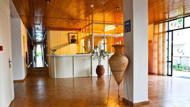 Eine Hotelhalle mit Holzboden, einer Rezeption und einer großen Vase.