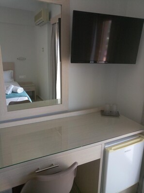 Une chambre d’hôtel comprenant un lit, un bureau avec un miroir, une télévision et un réfrigérateur.