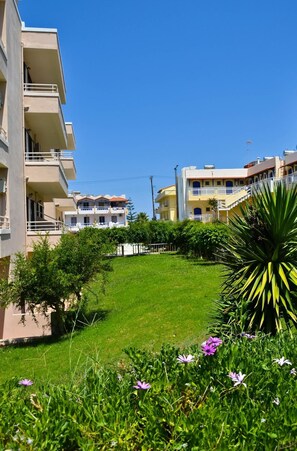 Un quartier résidentiel composé d’immeubles à plusieurs étages, d’une cour verdoyante et de quelques plantations.