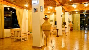 Eine geräumige Lobby mit Holzboden, einer großen Vase und einer Sitzecke mit Stühlen und einem Tisch.