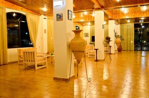 Un hall d’entrée spacieux, doté d’un plancher en bois, d’un grand vase et d’un espace détente avec des fauteuils et une table.
