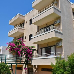 A multi-story building with balconies, air conditioning units, and a flowering plant. - Niko Elen Hotel (Hersonissos)